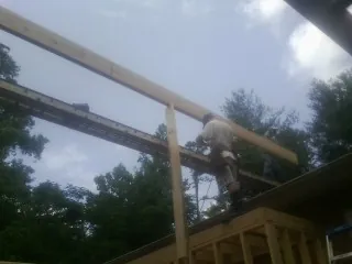 Carpenter setting a ridge beam over a new addition frame — Ice Dam Removal by Roofing Brothers in Bokeelia