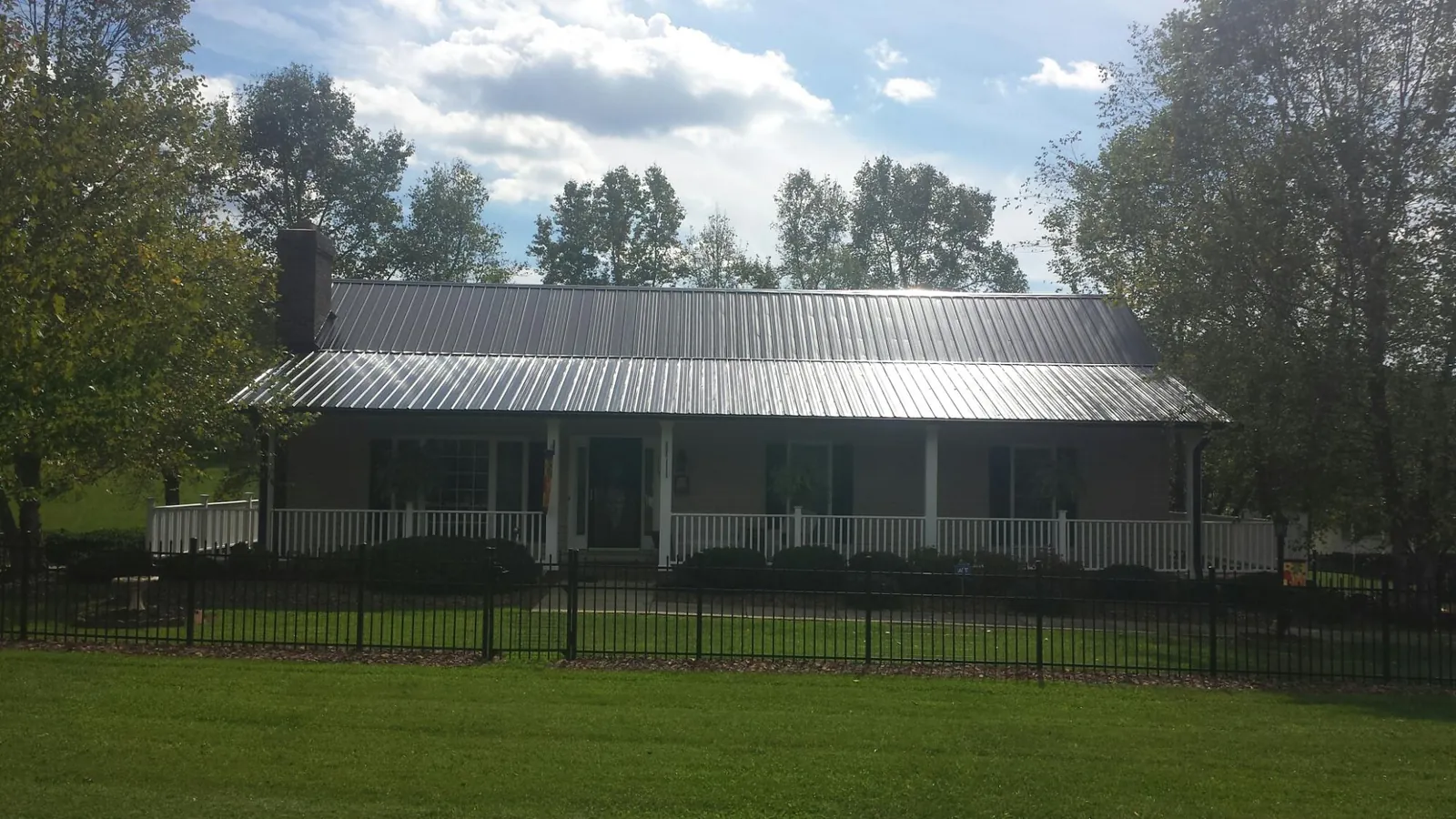 Gray metal roof on a brick ranch with a full width front porch — Gutter Guard Installation work by our crew in Bokeelia