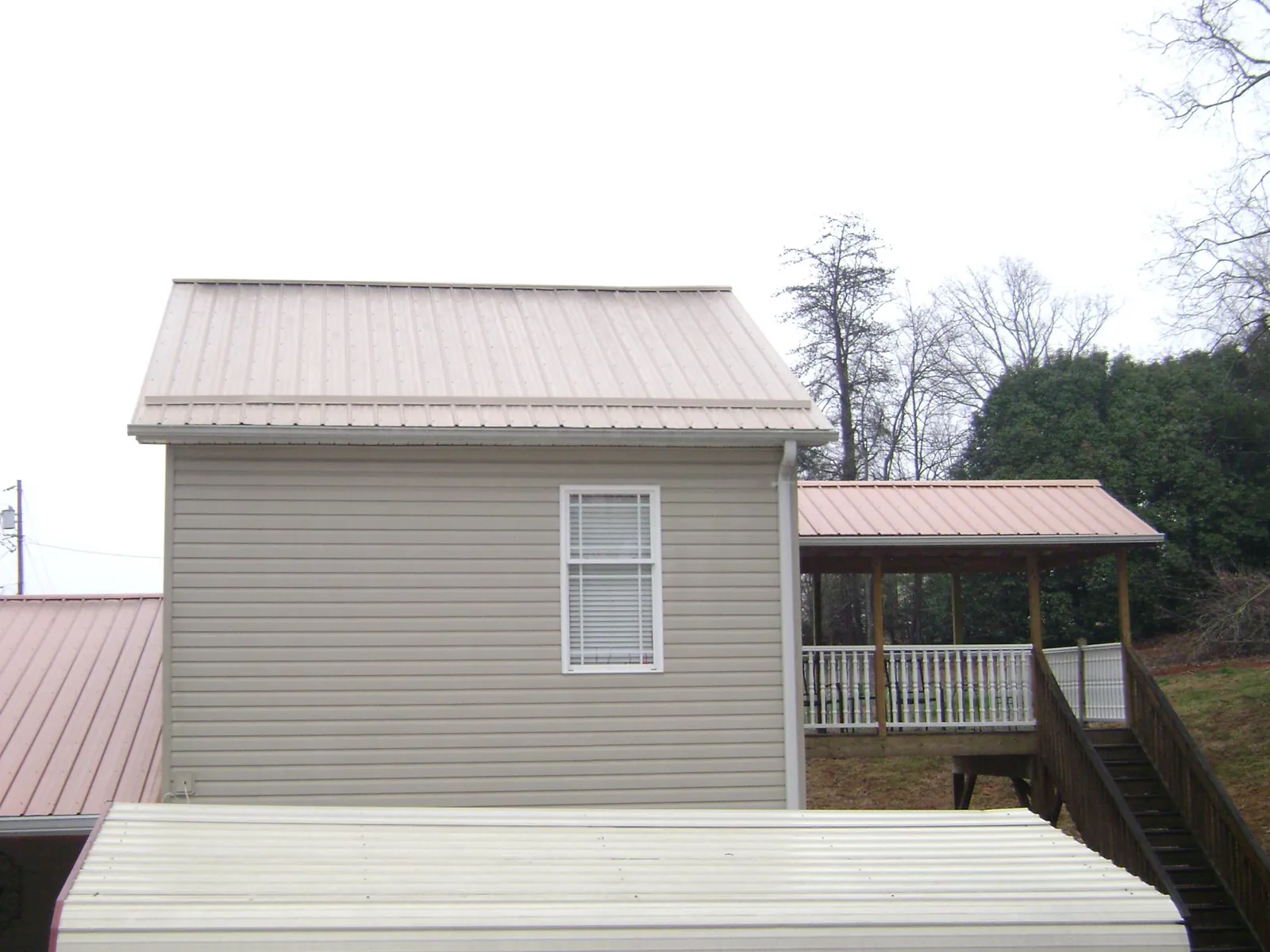 Tan metal roofs on a two story addition and attached porch, from a Roof Replacement job in Bokeelia