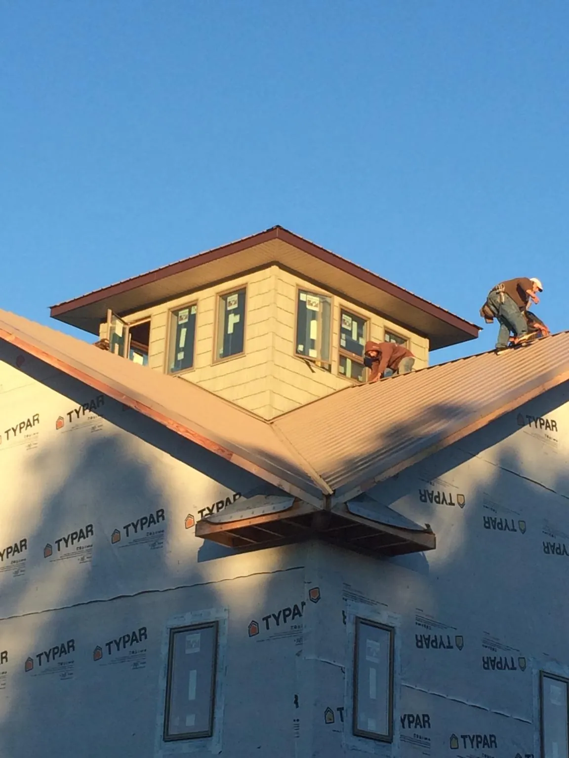 Roofers working around a rooftop cupola on a new metal roof at sunset — Roof Waterproofing in Bokeelia by Roofing Brothers